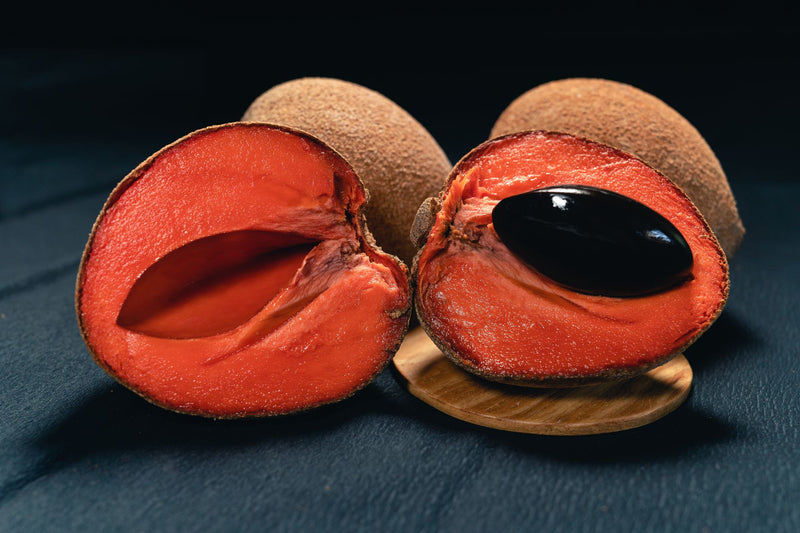 Mamey partido a la mitad con su pulpa naranja y el hueso oscuro al centro